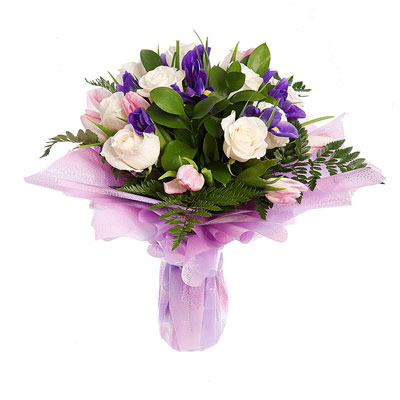 Нежный букет, составленный из 7 белых роз, 5 ирисов и 5 розовых тюльпанов, листьев папоротника и рускуса, в упаковке.